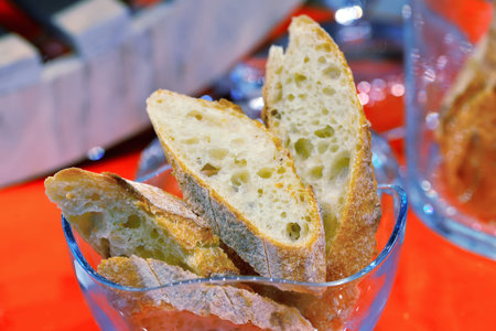 Cut pieces of white bread in a glass bowl on a red background.