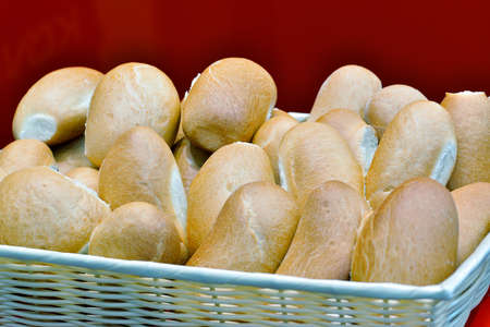 Many loaves in a wicker basket on a red background.の写真素材