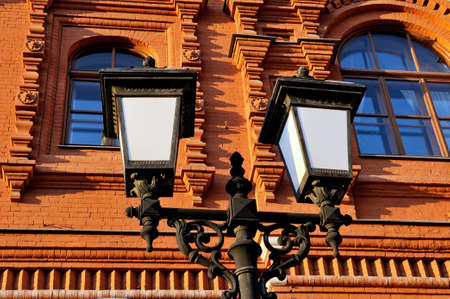 Old style street lamp against the building from a red brick.の写真素材