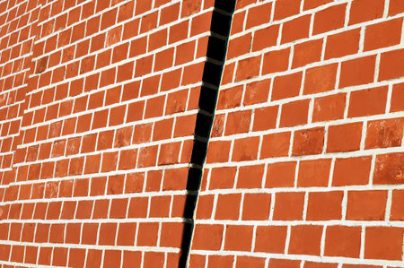 Red brick wall with white seams. The wall is lit with a sunlight a ledge on a wall in a shadow