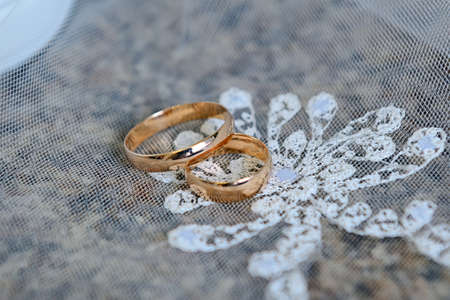 Gold wedding rings on a white lace veil.の写真素材