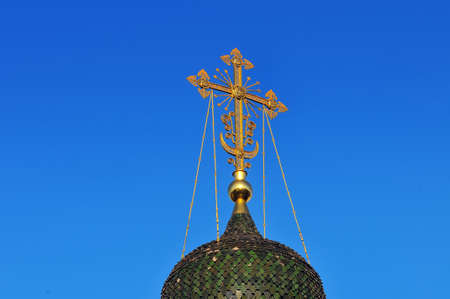 Green dome and gilded cross of Russian Orthodox Church against the background of the blue skyの写真素材