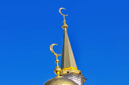 Gilded dome and spire Muslim mosque with a gilded crescent moon against a blue skyの写真素材