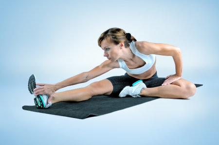 Sport fitness woman doing exercise on a black gym mat on a gray background. Studio shooting