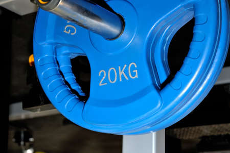Blue barbell plates with an inscription of 20 kg on a metal rack on a dark background in a sports, fitness club. Close upの写真素材