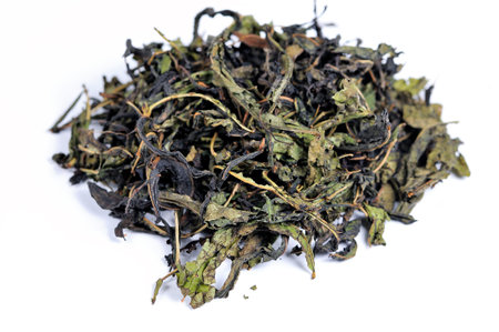 Dry tea leaves of herbal aromatic tea are scattered on a white background. Macro shooting, small...