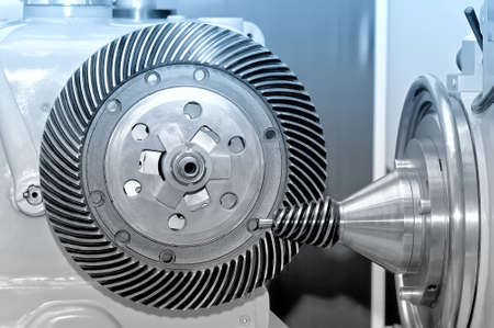Industrial machine with a conical gear and a circular gear, cogwheel with spiral machine teeth. Blue toned imageの写真素材