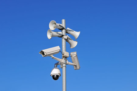 CCTV security cameras and loudspeakers against blue sky