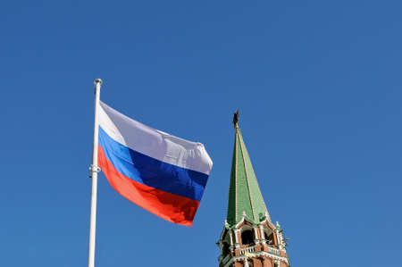 National flag of Russia against Troitskaya Tower of the Moscow Kremlin with a red star at top of a spire and blue skyの写真素材