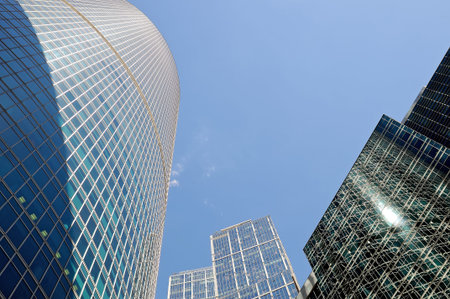 Modern skyscrapers made from glass and metal in downtown on a blue sky background. Bottom view.