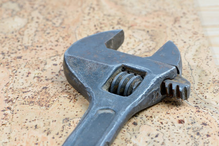 Dirty black adjustable wrench on a cork background. Old spanner. Close up