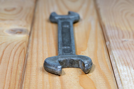 Old used wrench on a wooden background. Vintage spanner. Close up