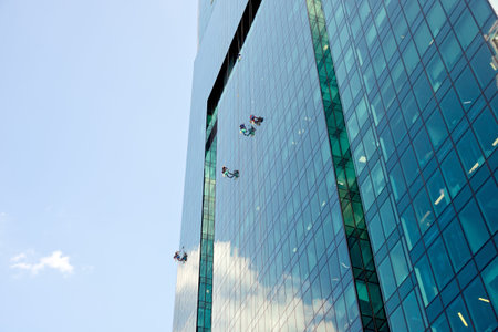 Moscow, Russia - May 28, 2019:  Industrial climbers washes glass on the facade of a skyscraper in...