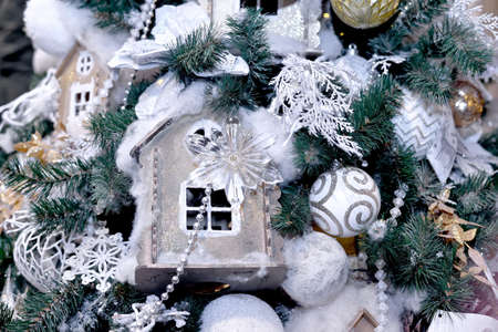 Ñardboard beige toy house decorated with cotton and Christmas toys hanging on Christmas and new year tree. Close-up.の写真素材