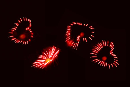 Celebratory fireworks in the form of red hearts against a twilight skyの写真素材