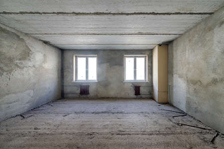 Empty living room in a country house without repair. Unfinished room with concrete walls and ceilingの写真素材