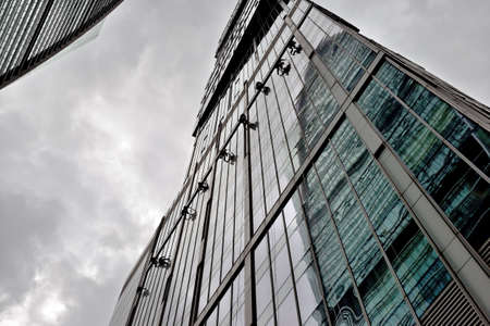 Industrial climber washes glass on the facade of a skyscraper. Industrial mountaineering, high-rise facade cleaning servicesの写真素材