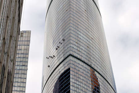 Industrial climber washes glass on the facade of a skyscraper. Industrial mountaineering, high-rise facade cleaning servicesの写真素材