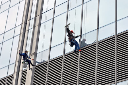 Moscow, Russia - April 29, 2021: Industrial climbers are washing glass on the facade of a skyscraper...