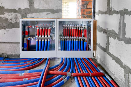 Heating system manifold valves for heat flooring and water supply in a country house. Pipes collector in a building under constructionの写真素材