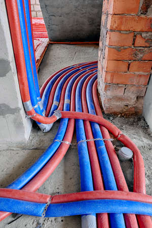 Red and blue pipes of the water supply and heating system in a country house under construction. Installation of a water supply system in a country houseの写真素材
