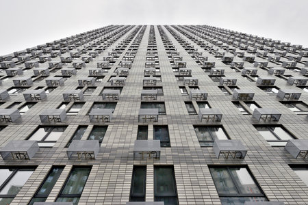 Modern high-rise apartment building. Gray house against a gray sky. Bottom view
