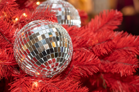 Silver mirrored Christmas ball on a red Christmas tree.