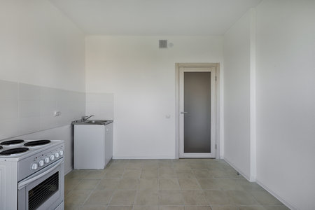 Kitchen with electric stove and sink after renovation. Kitchen in a new economy segment apartment without furnitureの写真素材