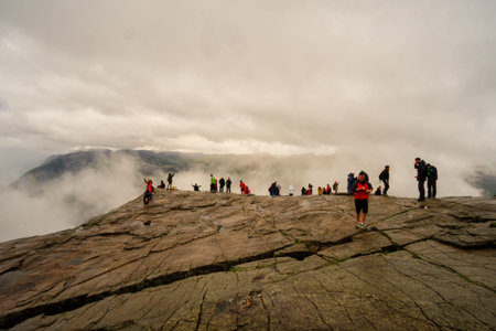 FORSAND, NORWAY - June, 2017. People at the top of Preikestolen (Pulpit Rock) on a cloudy day