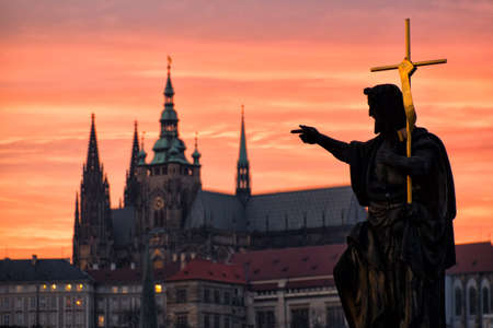 The statue of St. John the Baptist looks towards the Prague castleの写真素材
