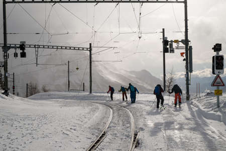 ALP GRUM, SWITZERLAND - January, 2018. Ski mountaineers on the Rhaetian railway tracks covered with snow in winter, after the passing of the Bernina Express trainのeditorial素材