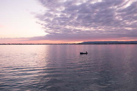 Syracuse, Italy - October, 2020. A small fishing boat at work in the Syracuse lagoon at sunsetの写真素材