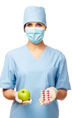 Young doctor holding some pills and apple, isolated white backgroundの写真素材