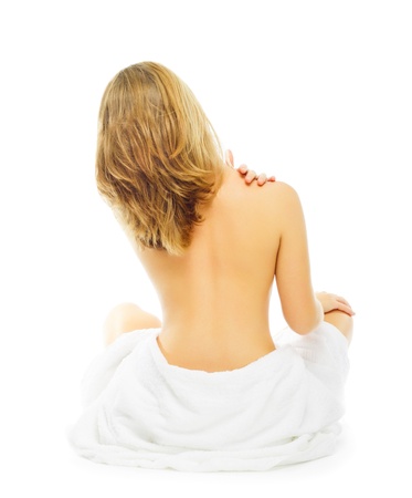 bare attractive blonde woman sitting back to camera with towel around bottomの写真素材