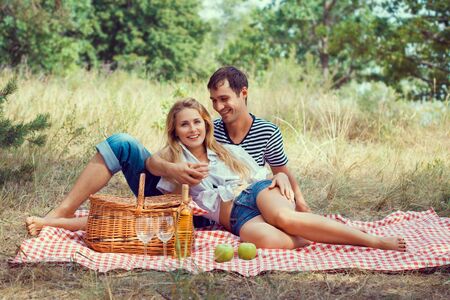 smiling young beautiful couple have a rest in wood on picnicの写真素材