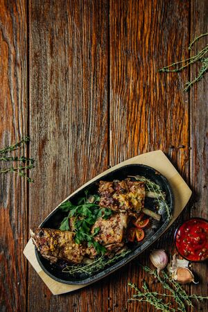 Spicy steak of the lamb chop iron pan. Food on dark wood background.の写真素材