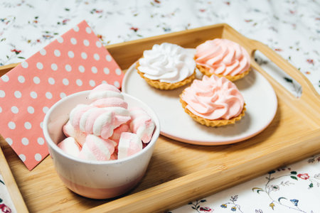 pink and white marshmallows on a wooden tray in bed