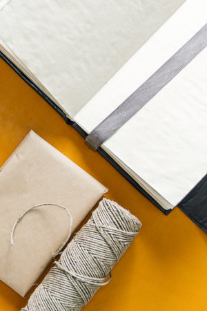 a notebook, a gift wrapped in paper, and a twine lie on yellow leather