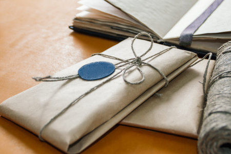 a gift wrapped in paper with a seal, and a twine lie on yellow leather