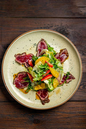 carpaccio plate on dark wooden table top viewの写真素材
