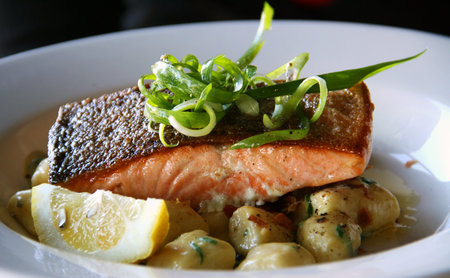 Salmon steak on top of potato balls garnish with green shallots and a slice of lemon
