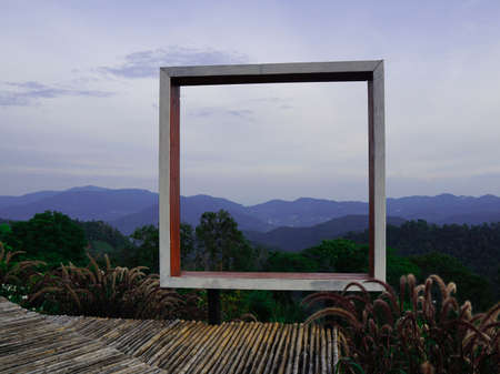 Take a photo with a square wooden frame and see the view. The old bamboo walkway is in the countryside with no terraces to prevent accidents on the background of forests and mountains.の写真素材