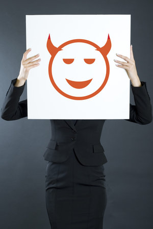 attractive businesswoman holding a devil boardの写真素材
