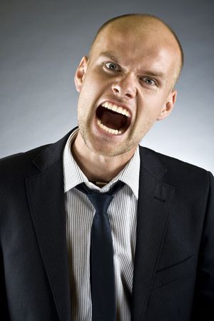 portrait of a young strong and screaming man isolated on dark  backgroundの写真素材