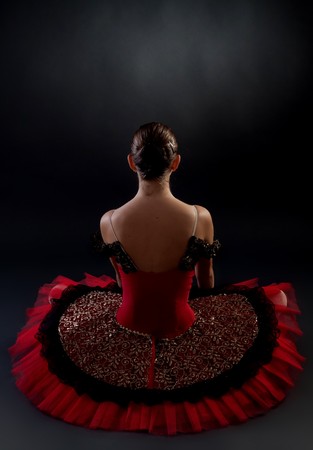 back picture of a seated ballerina on dark backgroundの写真素材