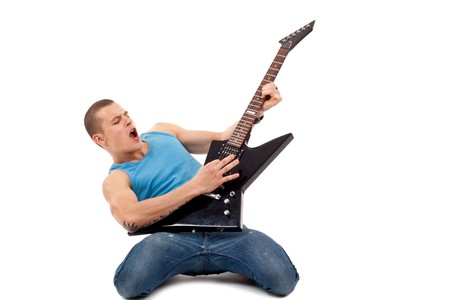 excited young man playing a guitar on his knees isolated against white background の写真素材