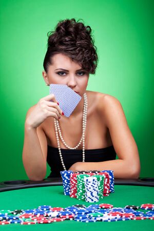 Beautiful Young Woman with Poker Chips in front of her and holding two cardsのeditorial素材