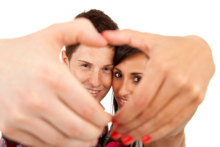 Couple making the shape of a heart with hands and looking through it
