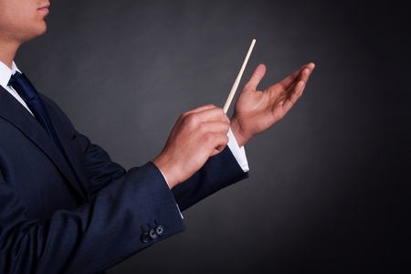 Cropped image of a male orchestra conductor directing with his baton in concertの写真素材