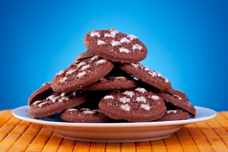 big pile of brown cookies on plate against blue backgroundの写真素材